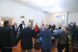 Guests standing in a circle enjoying live music in the upstairs function room at The Courthouse Hotel Smythesdale, with timber floors, high white ceilings and chandeliers.